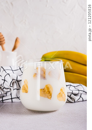 Alternative lactose free banana milk in a glass on the table vertical view Alternative lactose free banana milk in a glass on the table vertical view 121205816