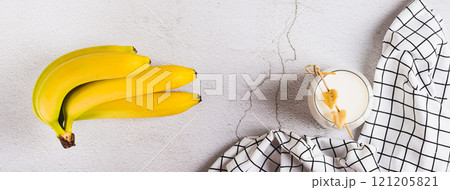 Banana vegan alternative milk in glass and fruits on table top view web banner Banana vegan alternative milk in glass and fruits on table top view web banner 121205821