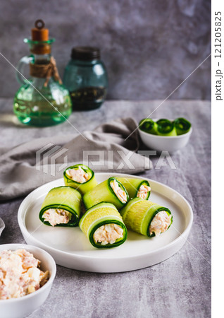 Appetizing cucumber rolls made from tuna salad, egg and cheese on a plate vertical view Appetizing cucumber rolls made from tuna salad, egg and cheese on a plate vertical view 121205825