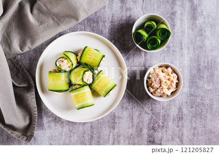 Appetizing cucumber rolls made from tuna salad, egg and cheese on a plate top view 121205827