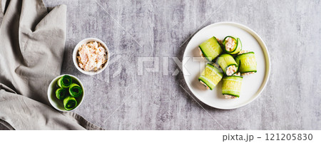 Cucumber rolls with fish salad on a plate on the table top view web banner 121205830