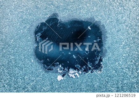 Frosted Window With a Clear Patch Revealing an Icy Blue Background During a Cold Winter Morning 121206519