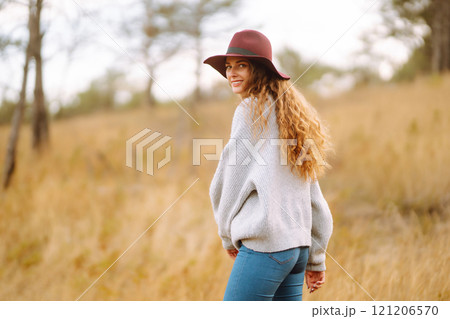Stylish woman in sweater and hat enjoys autumn nature. People, freedom, lifestyle, travel concept. Stylish woman in sweater and hat enjoys autumn nature. People, freedom, lifestyle, travel concept. 121206570