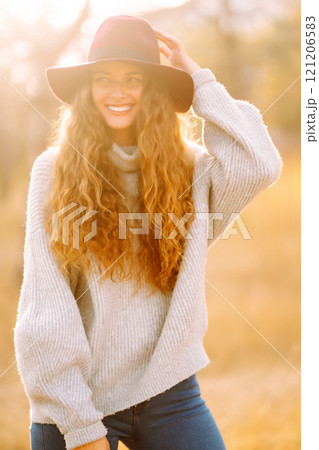 Stylish woman in sweater and hat enjoys autumn nature. People, freedom, lifestyle, travel concept. Stylish woman in sweater and hat enjoys autumn nature. People, freedom, lifestyle, travel concept. 121206583