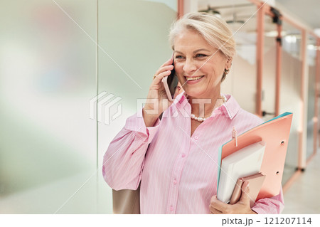 Portrait of smiling mature businesswoman dressed in elegant pink shirt for office work talking on phone in hallway of modern coworking space, copy space 121207114