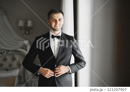 Grooms morning preparation. Handsome man getting dressed and preparing for the wedding 121207907