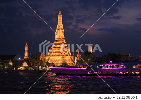 Wat Arun Temple illuminated at night with cruise boat and nice reflections in the river in Bangkok, Thailand 121208061