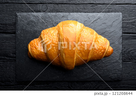 Close-up of freshly baked croissant on black plate 121208644