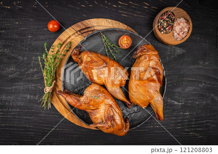 Smoked quails with herbs and spices on a ceramic plate on a dark background. top view Smoked quails with herbs and spices on a ceramic plate on a dark background. top view 121208803
