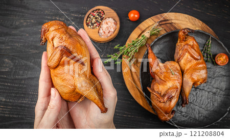 Female hands holding smoked quail, Delicious meat with spices and herbs. top view 121208804