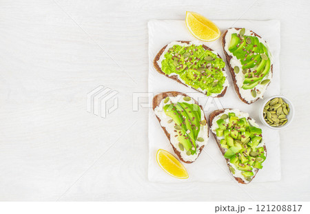 A set of delicious avocado toasts with rye bread, cheese, pumpkin, nut and sesame for breakfast or lunch. Vegetarian food. Vegan menu. top view 121208817