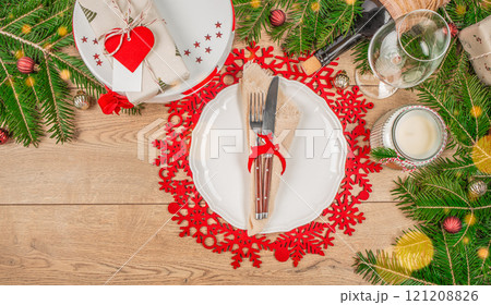 Christmas table setting with white plate, gift, golden balls on wooden background. Xmas festive dinner. Top view. Copy space Christmas table setting with white plate, gift, golden balls on wooden background. Xmas festive dinner. Top view. Copy space 121208826