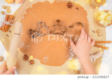 Cooking Christmas cookies family background. Children's hands cutting shapes. Gingerbread man. Top view Cooking Christmas cookies family background. Children's hands cutting shapes. Gingerbread man. Top view 121208827