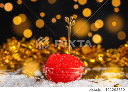 Salmon Red Caviar in bowl on a festive table with defocused Christmas lights at background. Luxury delicacy food, copy space 121208850