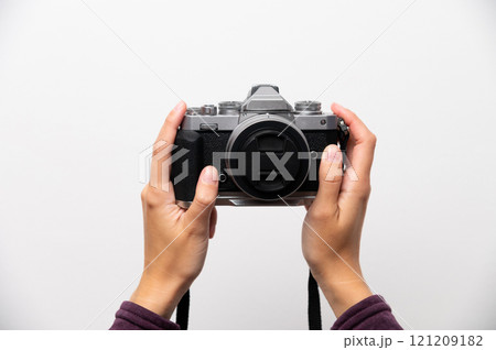 Hand holding classic retro style camera in modern assembly, on white background, front view, retro updated things concept 121209182