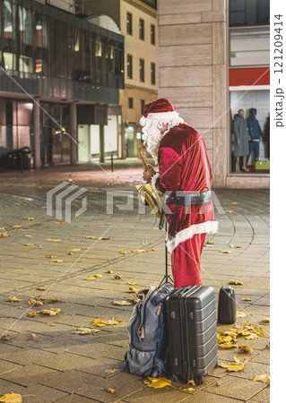 Santa Claus playing saxophone on a city street. Concept of festive street performance, holiday entertainment 121209414