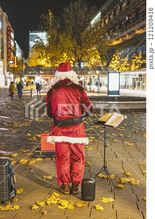 Santa musician performs outdoors in festive urban setting during the holiday season 121209416