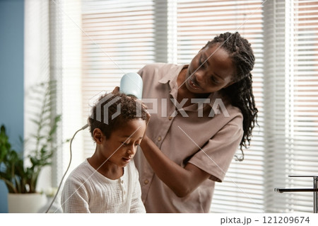 Caring young mother helping little son with drying hair in bathroom during daily hygiene routine, copy space 121209674