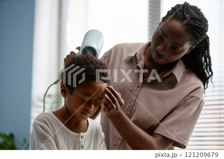 Young Black woman taking care of little son drying kids hair after shower during daily hygiene routine in bathroom, copy space 121209679