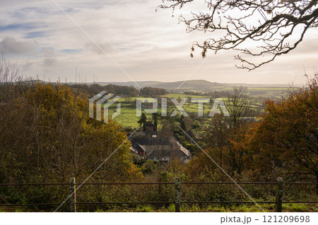 View of the English countryside near Shaftesbury, Dorset with fields, trees, hills and a farm. 121209698