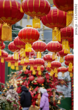 Rows of traditional red Chinese lanterns hanging above a festive crowd, celebrating cultural event in vibrant colors Rows of traditional red Chinese lanterns hanging above a festive crowd, celebrating cultural event in vibrant colors 121209992