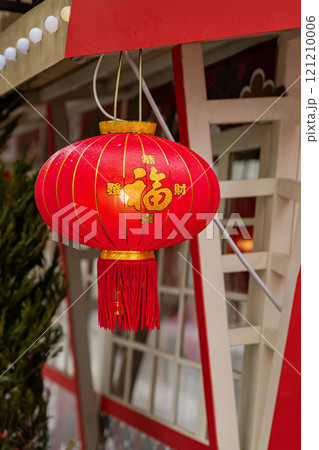 Red lantern hanging outside building, symbol prosperity of festive celebration. Translation: "Wealth" Red lantern hanging outside building, symbol prosperity of festive celebration. Translation: "Wealth" 121210006