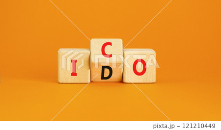 Initial coin or DEX offering symbol. Concept words abbreviation ICO or IDO on wooden block. Beautiful orange table orange background. Business Initial coin or DEX offering concept. Copy space. 121210449