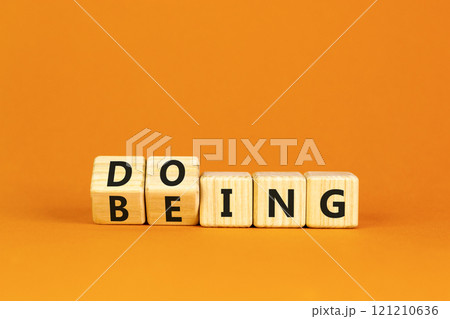 Doing or being symbol. Concept word Doing and Being on wooden cubes. Beautiful orange table orange background. Business doing or being concept. Copy space. Doing or being symbol. Concept word Doing and Being on wooden cubes. Beautiful orange table orange background. Business doing or being concept. Copy space. 121210636