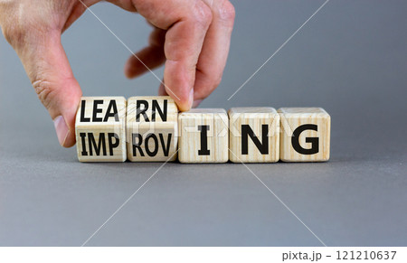 Improving or learning symbol. Businessman turns wooden cubes and changes the word Improving to Learning . Beautiful grey background. Educational business improving or learning concept. Copy space. Improving or learning symbol. Businessman turns wooden cubes and changes the word Improving to Learning . Beautiful grey background. Educational business improving or learning concept. Copy space. 121210637