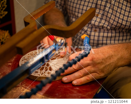 hands of a craftsman cut out a pattern from wood with a jigsaw hands of a craftsman cut out a pattern from wood with a jigsaw 121211044