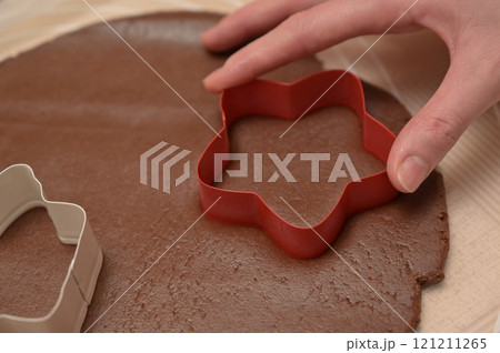 Christmas homemade baking, close-up woman hand cuts out dough for baking gingerbread 121211265