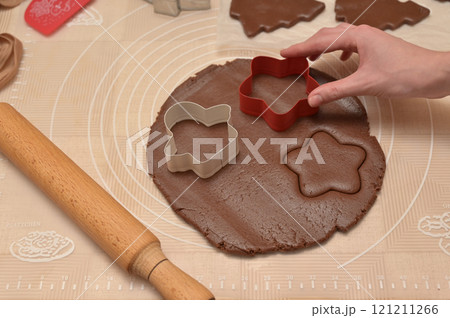 Christmas homemade baking, woman hand cuts out dough for baking gingerbread, cutter, rolling pin, spatula on the table Christmas homemade baking, woman hand cuts out dough for baking gingerbread, cutter, rolling pin, spatula on the table 121211266