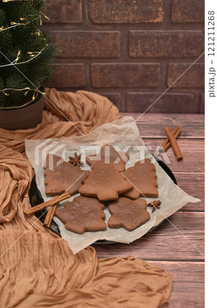 Christmas homemade baking, gingerbread cookies with spices on the wooden table, tree near brick wall, cloth on a background Christmas homemade baking, gingerbread cookies with spices on the wooden table, tree near brick wall, cloth on a background 121211268