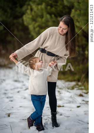 Happy smiling mother and little girl have a fun in nature park during Christmas holiday. First snow Happy smiling mother and little girl have a fun in nature park during Christmas holiday. First snow 121211413