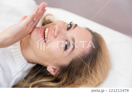 Close up face of beautiful woman lying on spa bed after procedure in cosmetology clinic 121211479