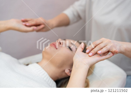 Healer launches body energy through hands before access bars therapy with young woman, stimulating positive change thoughts and emotions. Alternative medicine concept. 121211502
