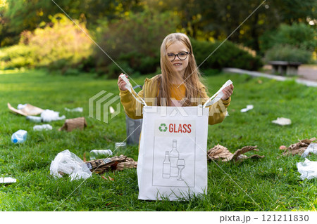 Girl working in park collecting trash and participating in charity cleanup activity 121211830