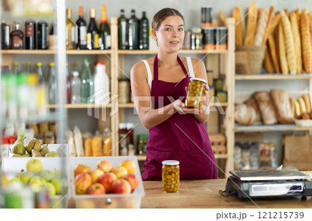 Young woman seller offering olives in grocery store 121215739
