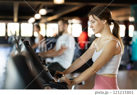 Young woman exercising on exercise bike in gym Young woman exercising on exercise bike in gym 121215801