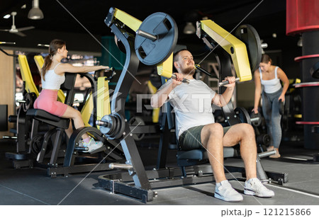 Young man training his arms on machine Young man training his arms on machine 121215866