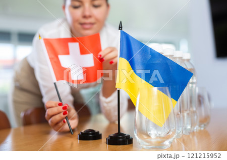 Flags of Ukraine and Switzerland in female hands on negotiating table Flags of Ukraine and Switzerland in female hands on negotiating table 121215952