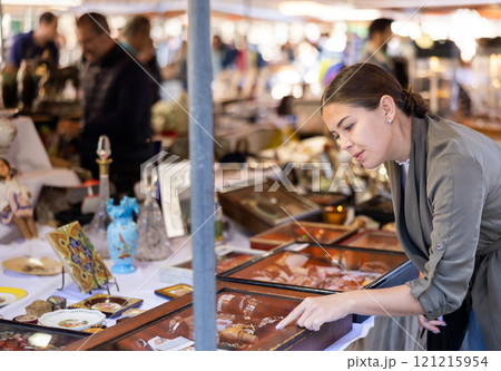 Cheerful female tourist choosing antique jewelry at flea market Cheerful female tourist choosing antique jewelry at flea market 121215954