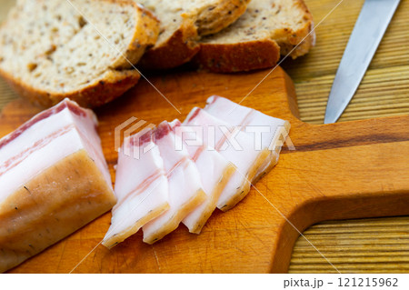 There is pound of lard and several sliced slices on cutting board. There is pound of lard and several sliced slices on cutting board. 121215962