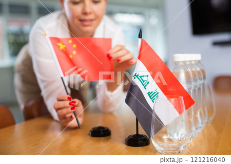 Employee of delegation prepares negotiating table - sets up flag of China and Iraq Employee of delegation prepares negotiating table - sets up flag of China and Iraq 121216040
