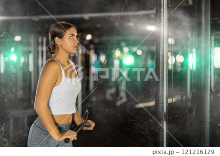 Young woman exercising her arms on cable machine Young woman exercising her arms on cable machine 121216129