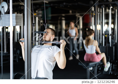 Young man training his arms on machine Young man training his arms on machine 121216246