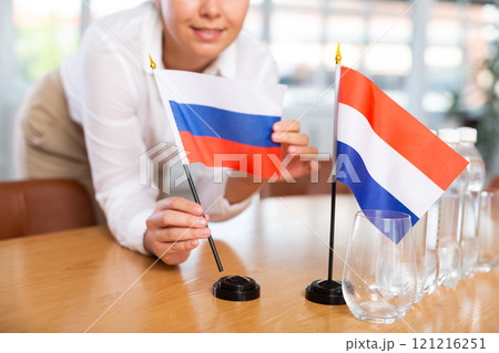 Employee of delegation prepares negotiating table - sets up flag of Russia and Netherlands 121216251