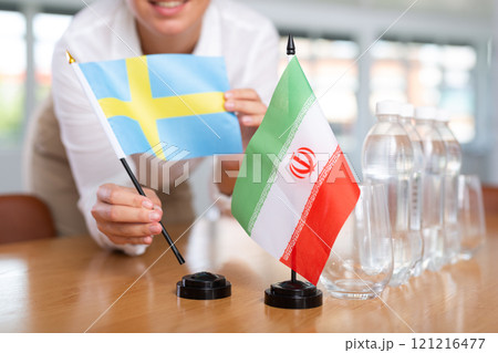 Employee of delegation prepares negotiating table - sets up flag of Iran and Sweden Employee of delegation prepares negotiating table - sets up flag of Iran and Sweden 121216477