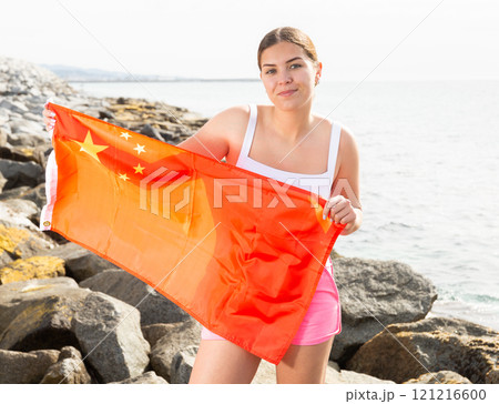 Young woman on coast posing with flag of China Young woman on coast posing with flag of China 121216600