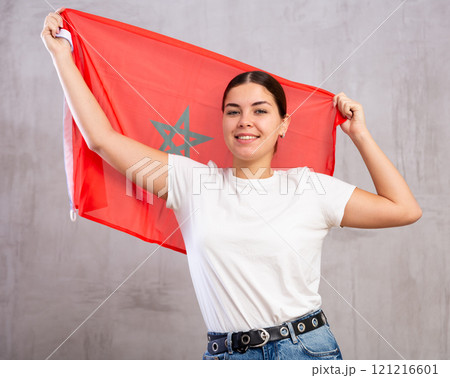 Happy young woman stands with flag of Morocco. Isolated 121216601